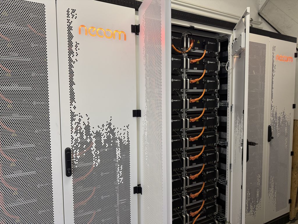 Offener weißer Serverschrank mit orangefarbenen Kabeln und dem Schriftzug 'neoom'