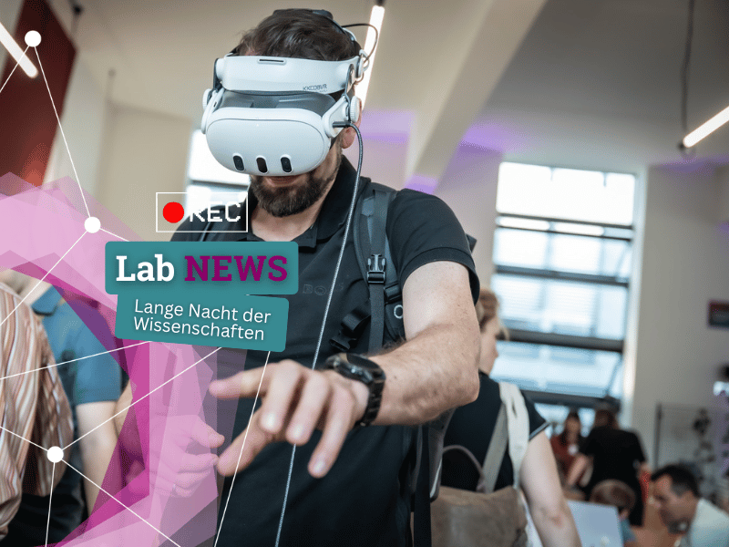 Mann mit Virtual-Reality-Brille und schwarzem T-Shirt in einem hellen Raum mit mehreren Personen im Hintergrund