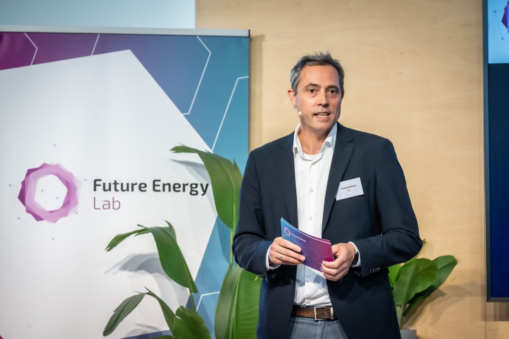 Mann in dunklem Sakko hält Notizen und spricht vor Banner mit Schriftzug 'Future Energy Lab'